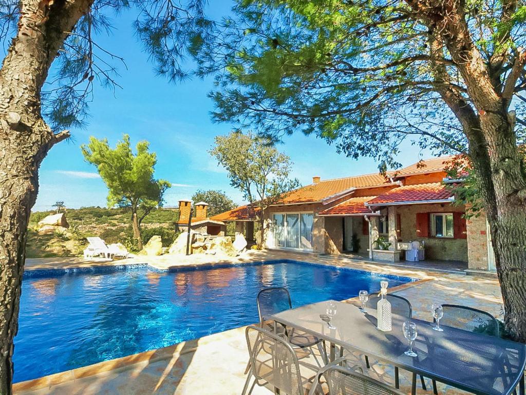 a pool with a table and chairs next to a house at Holiday Home Villa Sandra by Interhome in Kruševo