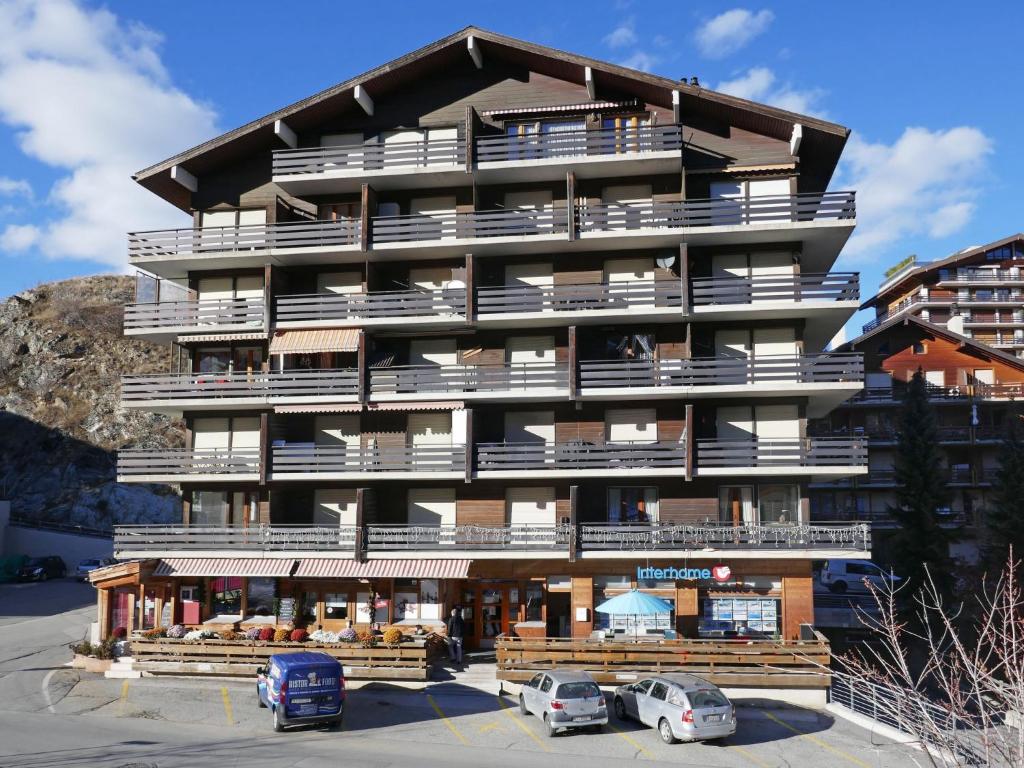 ein großes Gebäude mit davor geparkt in der Unterkunft Apartment Beau-Séjour 24 by Interhome in Nendaz