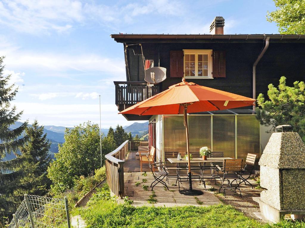 a house with a deck with a table and an umbrella at Chalet Bühlweidli by Ferienlenk in Lenk