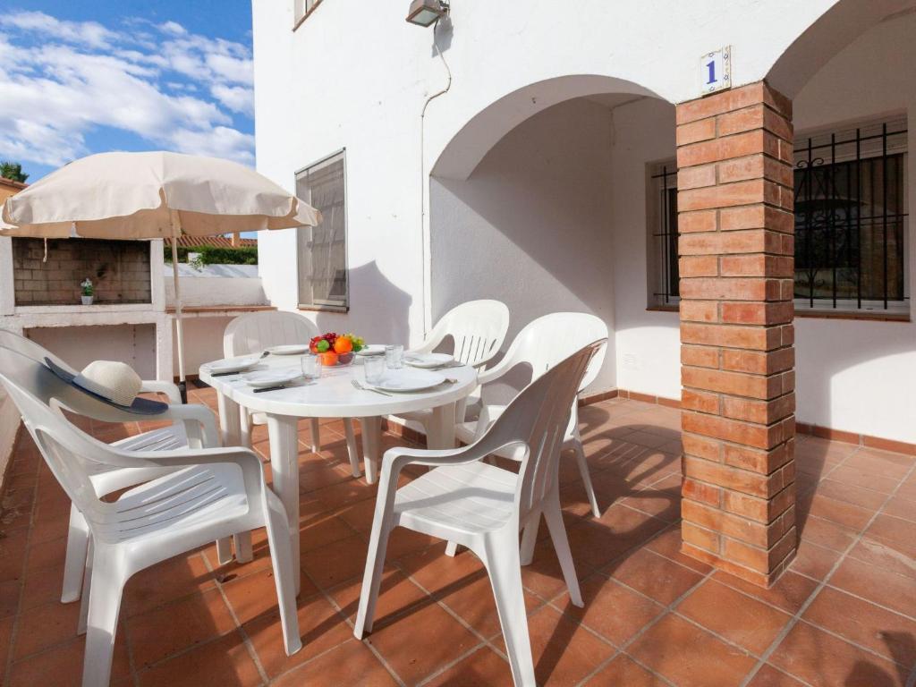 un patio con una mesa y sillas blancas y una sombrilla en Apartment Anfora 1 by Interhome, en Sant Martí d’Empúries