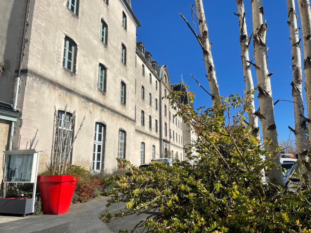 a large building with a red bucket in front of it at Logis Hôtel Ancien Grand Séminaire in Saint-Flour