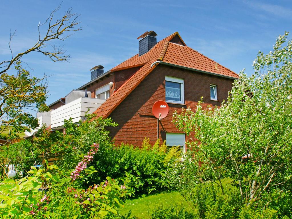 a house with a red roof and some bushes at Apartment Fischerstube by Interhome in Norddeich