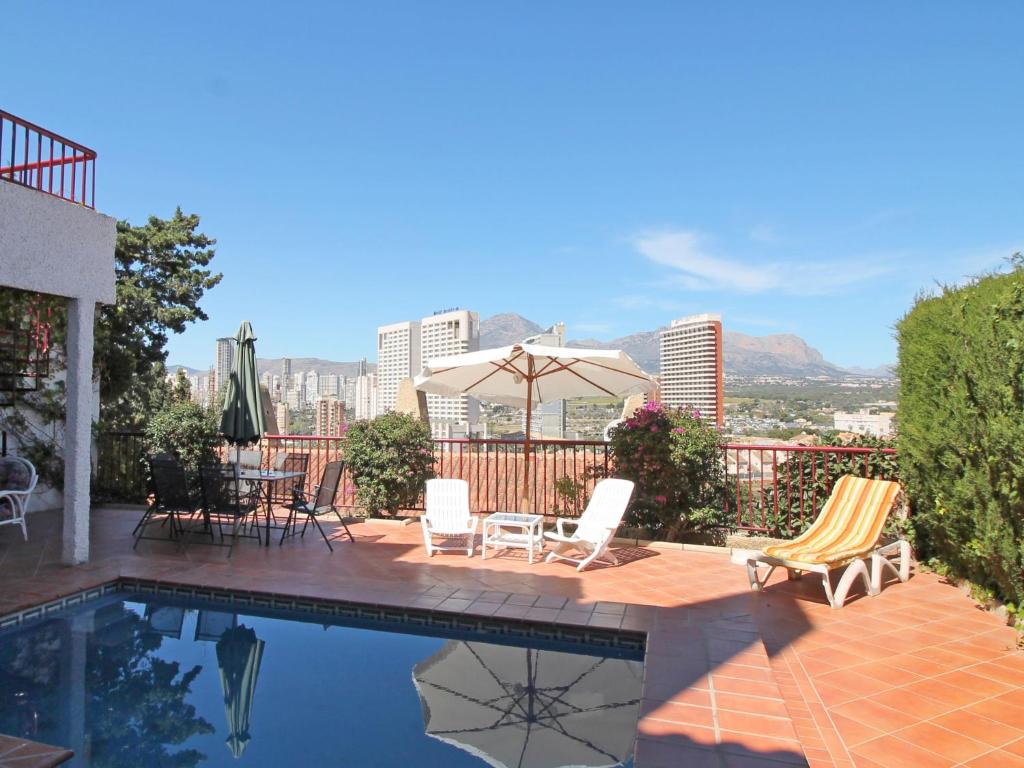 a patio with chairs and a pool with a view of the city at Holiday Home Mar y Montaña by Interhome in Benidorm