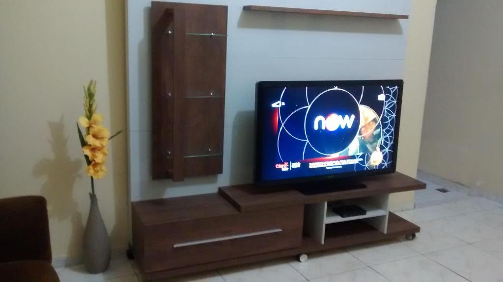 TV en una sala de estar con soporte de madera en Casa Temporada Juazeiro Bahia, en Juazeiro
