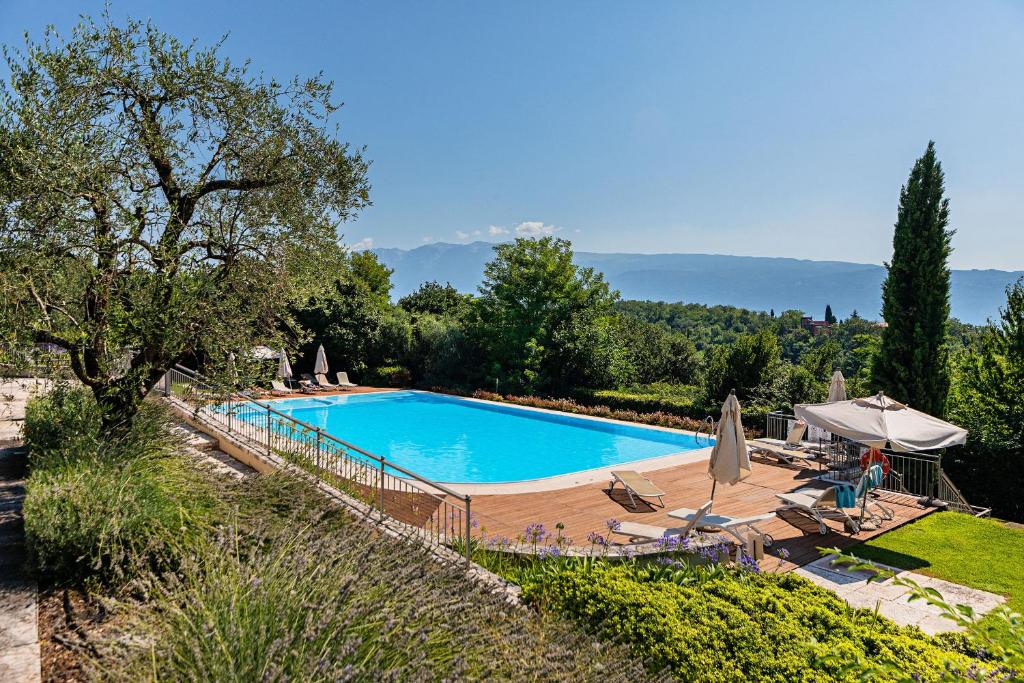 una piscina con sedie e ombrelloni in un cortile di Villa Valeria con piscina by Wonderful Italy a Toscolano Maderno