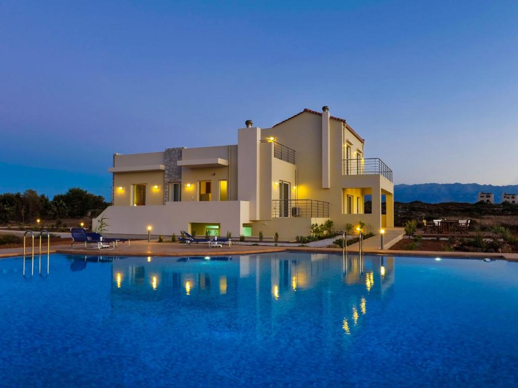 a large house with a large swimming pool at night at Cretan View Apartments with sea view in Stavros
