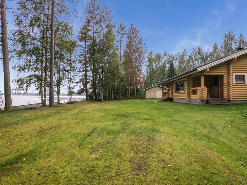 uma cabana de madeira com um grande quintal em frente a uma casa em Holiday Home Uitonniemi- rummukkala by Interhome em Polvijärvi