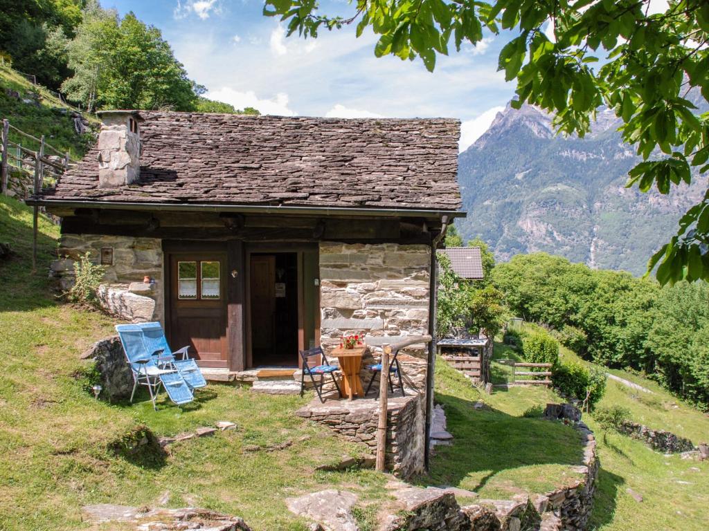 Cabaña pequeña de piedra con montañas en el fondo en Holiday Home Rustico Fey by Interhome, en Malvaglia