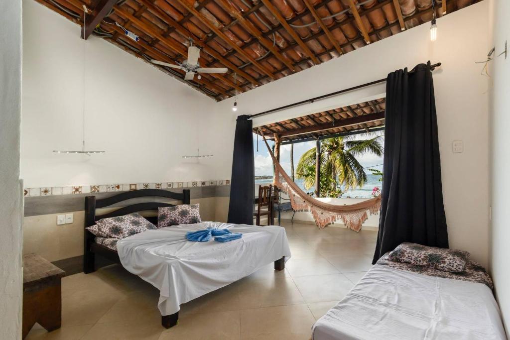 a room with two beds and a hammock in it at Pousada Aguas Marinhas in Cabo de Santo Agostinho