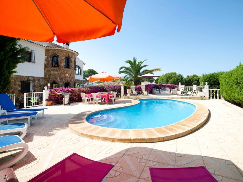 uma piscina com mesas e cadeiras e um guarda-sol em Villa Cathy & Marianne by Interhome em Casas de Torrat
