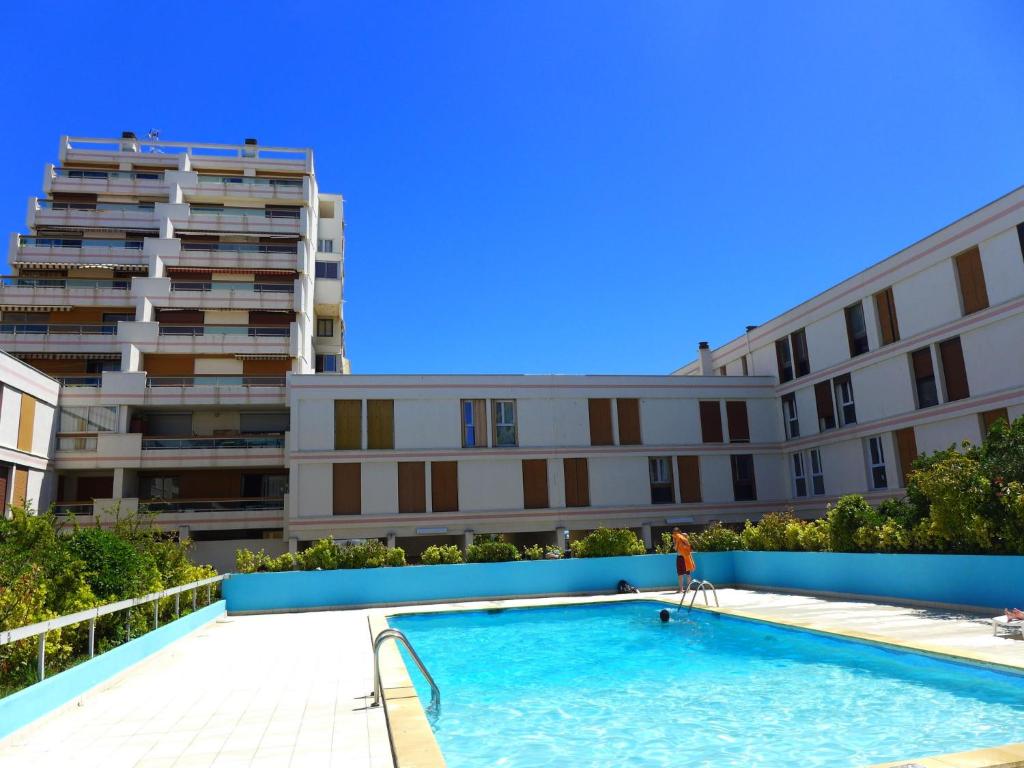 une personne assise sur une chaise dans une piscine à côté d'un bâtiment dans l'établissement Studio Chéops-2 by Interhome, à La Grande Motte