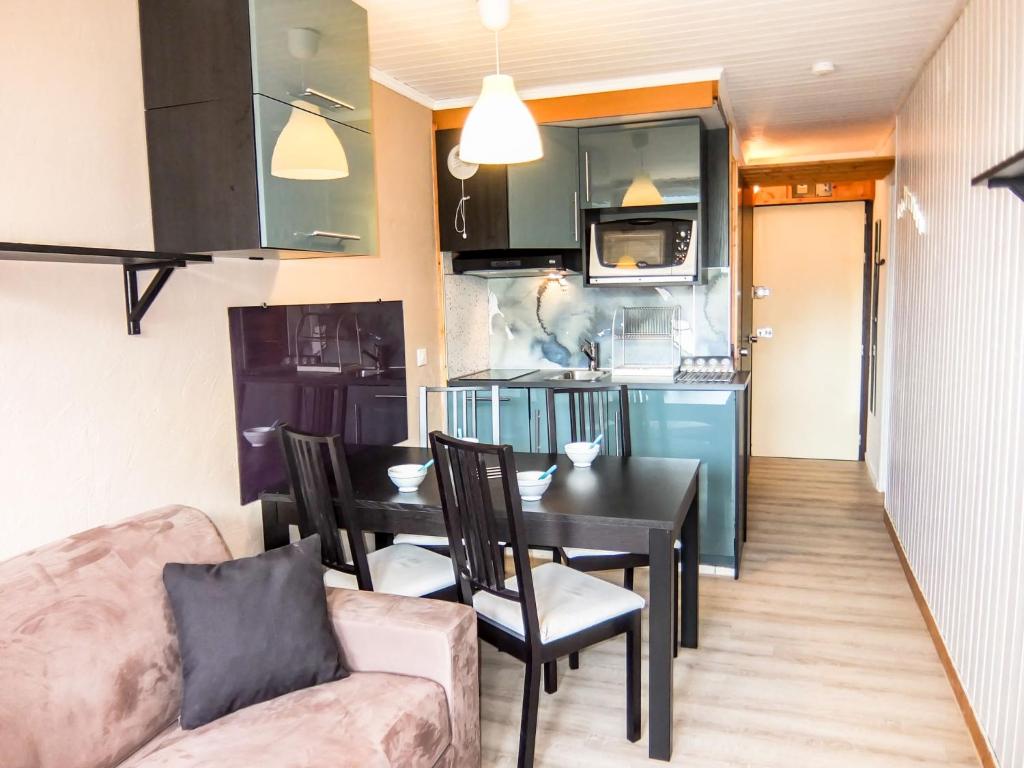 a living room with a dining room table and a kitchen at Apartment Villaret 604 by Interhome in Les Menuires