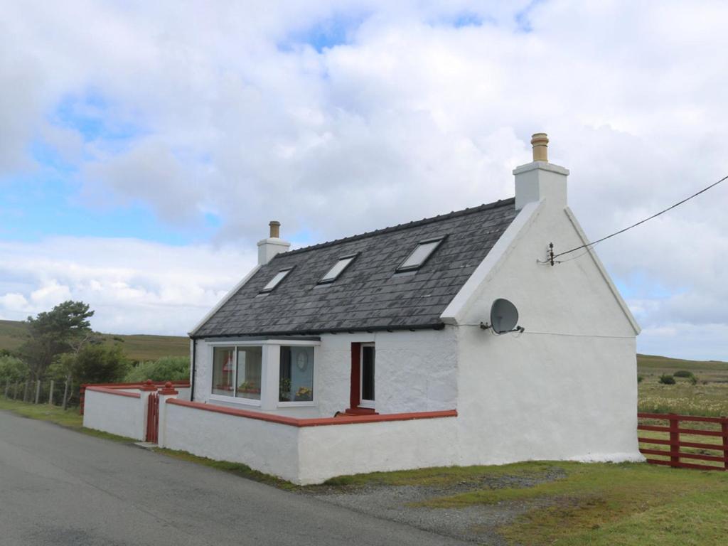 a white house with a black roof on the side of a road at Holiday Home Flo Anndra by Interhome in Kilmaluag