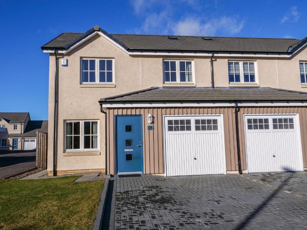 una casa con dos puertas de garaje en una entrada en Holiday Home Devonvale Place by Interhome en Kinross