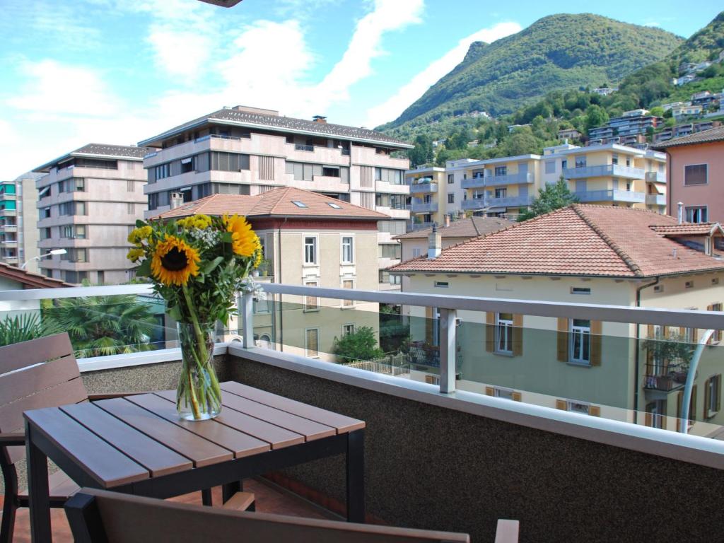 um vaso de flores sentado numa mesa na varanda em Studio Shina em Lugano