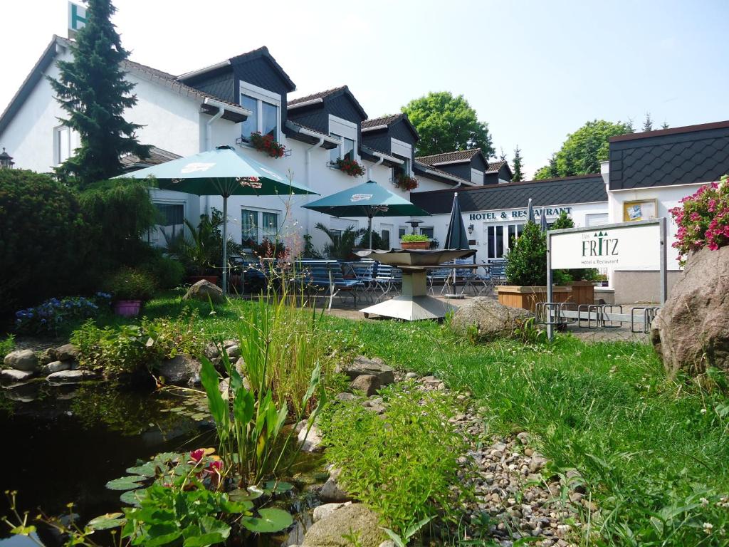 a hotel with a pond and tables and umbrellas at Das FRITZ Hotel in Schwerin