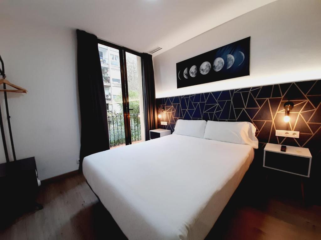 Un dormitorio con una gran cama blanca y una ventana en Hostal Laia by gaiarooms, en Barcelona