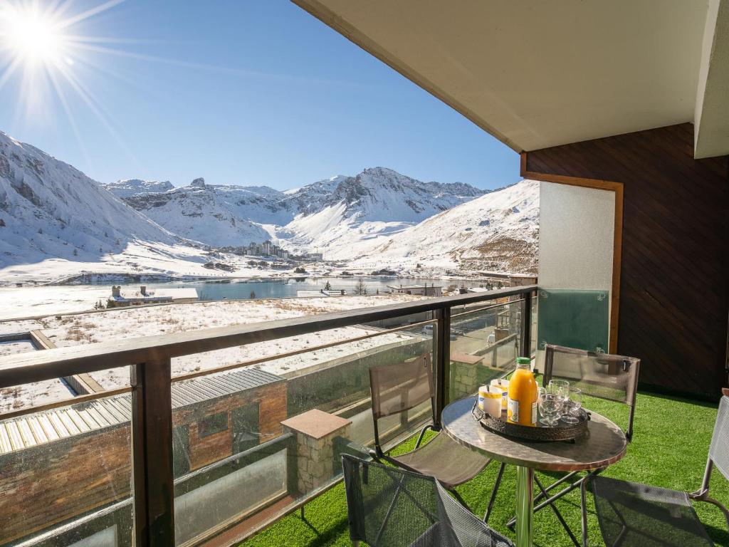 a balcony with a table and chairs and snow covered mountains at Apartment Les Cimes - Le Lac by Interhome in Tignes