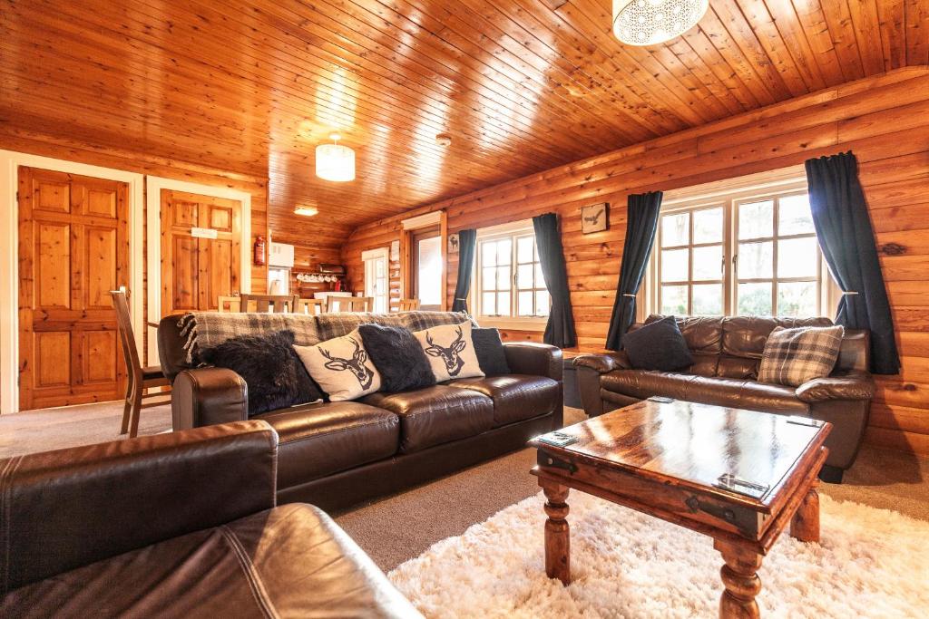 a living room with a leather couch and a coffee table at Brenin 3 Bedroom Lodge -Snowdonia in Tanygrisiau