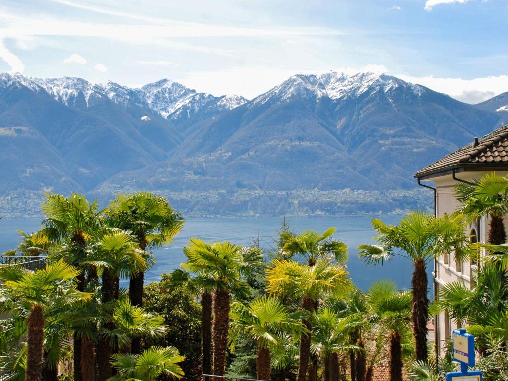 a view of a mountain range with palm trees and a building at Apartment Condominio Les Hirondelles by Interhome in Orselina