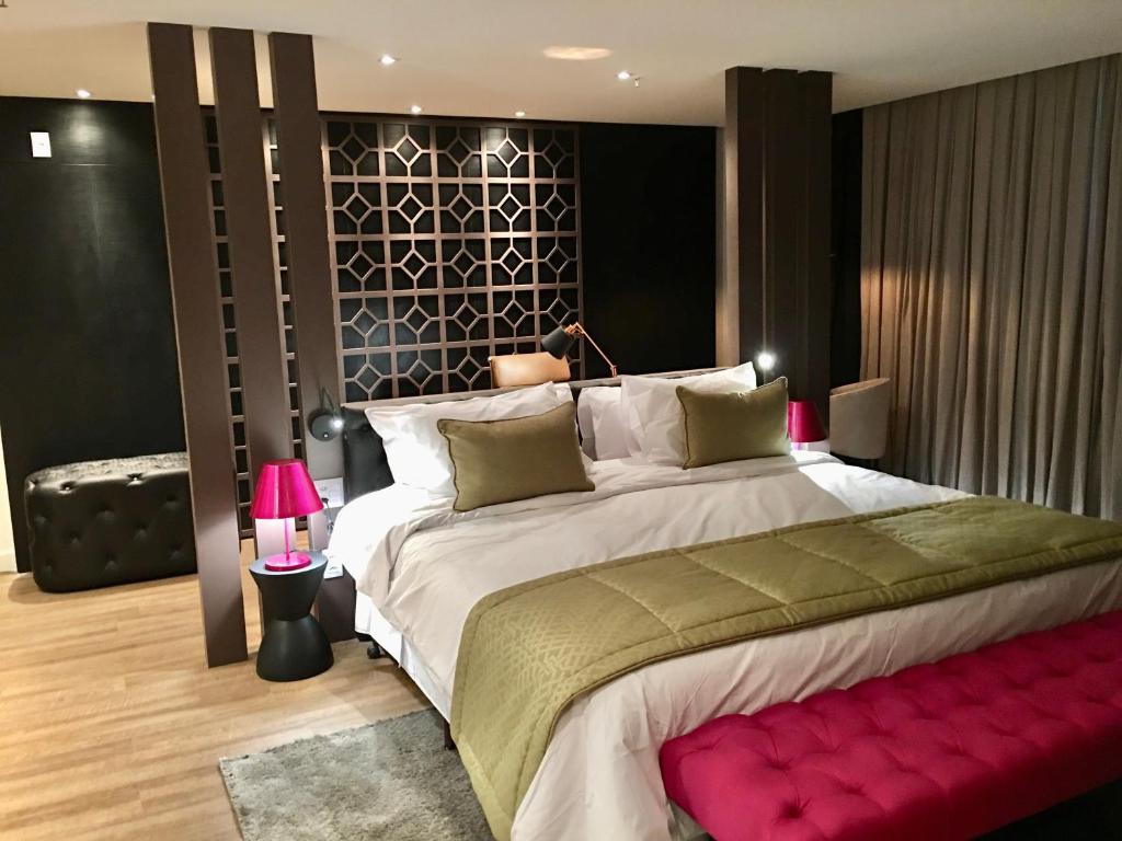 a bedroom with a large bed with a red bench at QS Marista Hotel in Goiânia