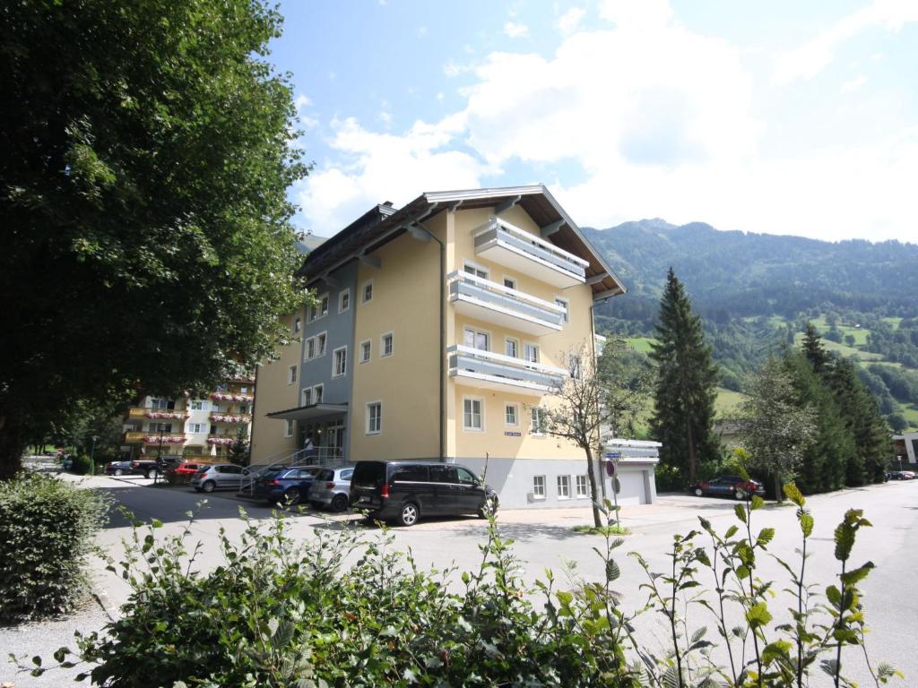 a large yellow building with cars parked in a parking lot at Apartment Stefanie Top 6 by Interhome in Bad Hofgastein