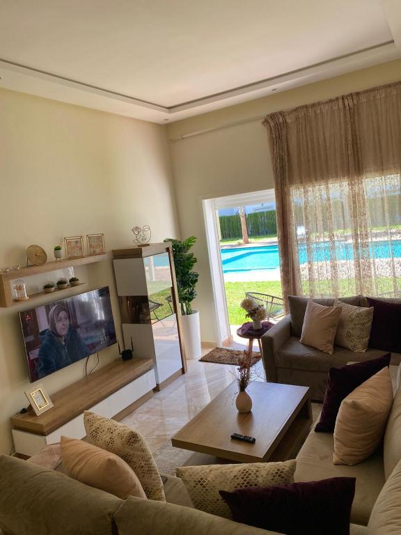un soggiorno con un divano e una TV di Apparemment de luxe vue piscine a Bouznika