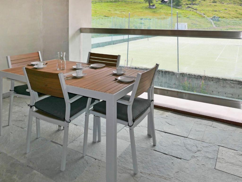einen Holztisch und Stühle mit einem großen Fenster in der Unterkunft Apartment Rosablanche E 108 by Interhome in Siviez