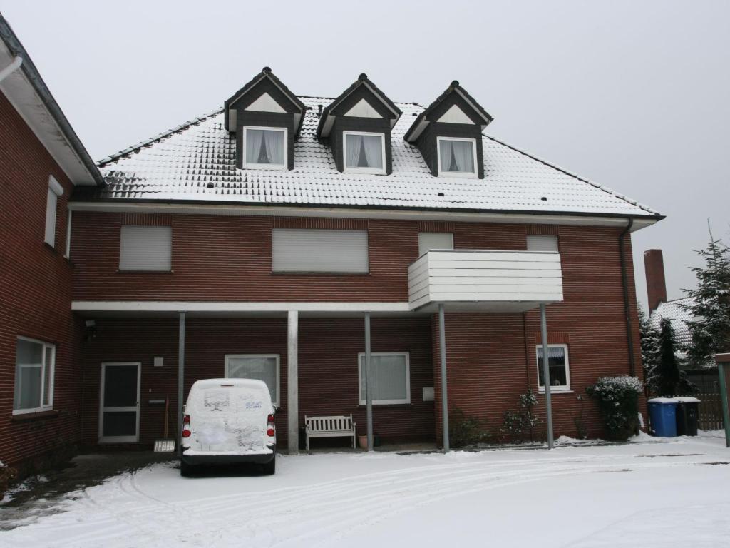 ein rotes Backsteinhaus mit einem weißen Van im Schnee in der Unterkunft Apartment Lachmöwe by Interhome in Norddeich