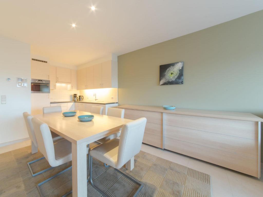 eine Küche mit einem Holztisch und weißen Stühlen in der Unterkunft Apartment Seaside 4-02 by Interhome in Bredene