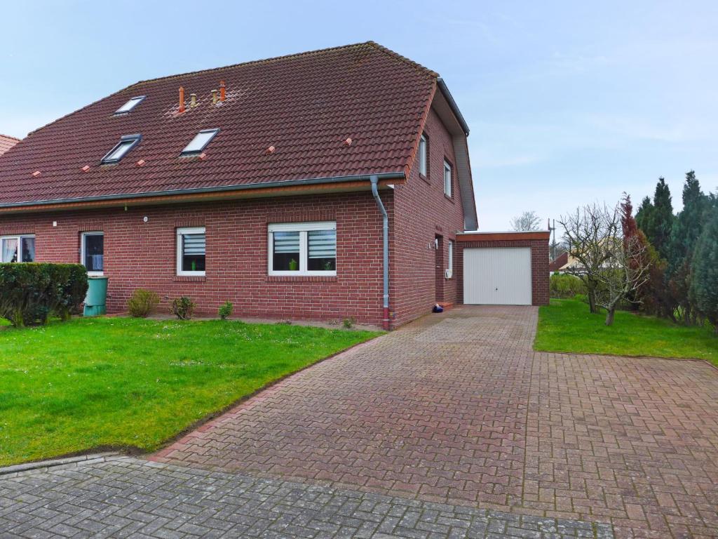 a red brick house with a white garage at Holiday Home Nilles by Interhome in Norddeich