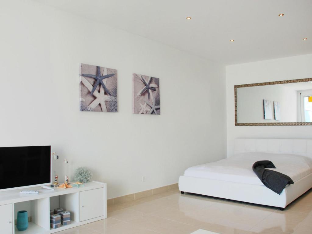 um quarto branco com uma cama e uma televisão de ecrã plano em Apartment Residenza Solemonte by Interhome em Locarno