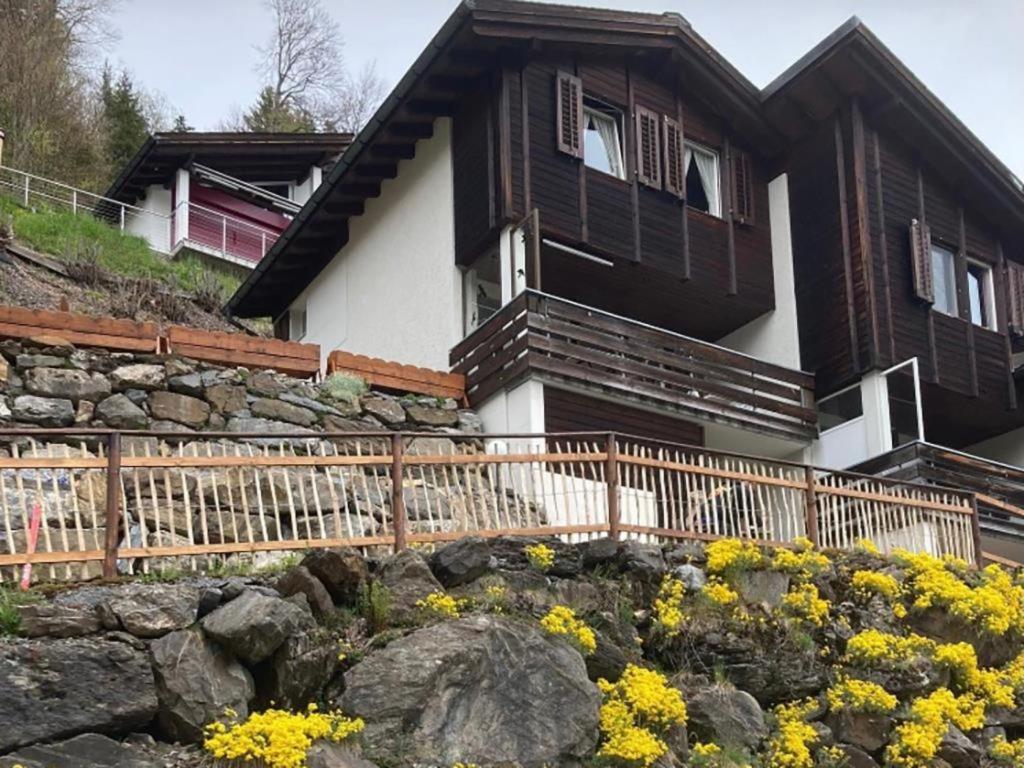 uma casa com uma cerca e flores à frente dela em Apartment Chalet Murmeli by Interhome em Engelberg