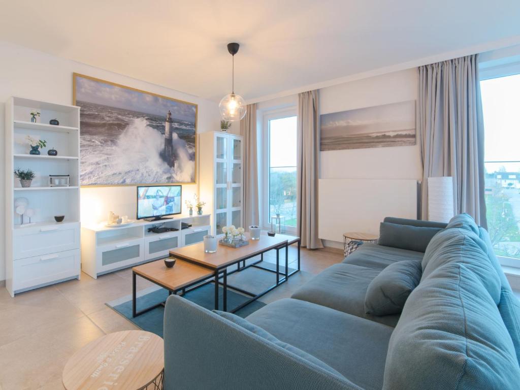 a living room with a blue couch and a table at Apartment Pura vida with balcony by Interhome in Bredene