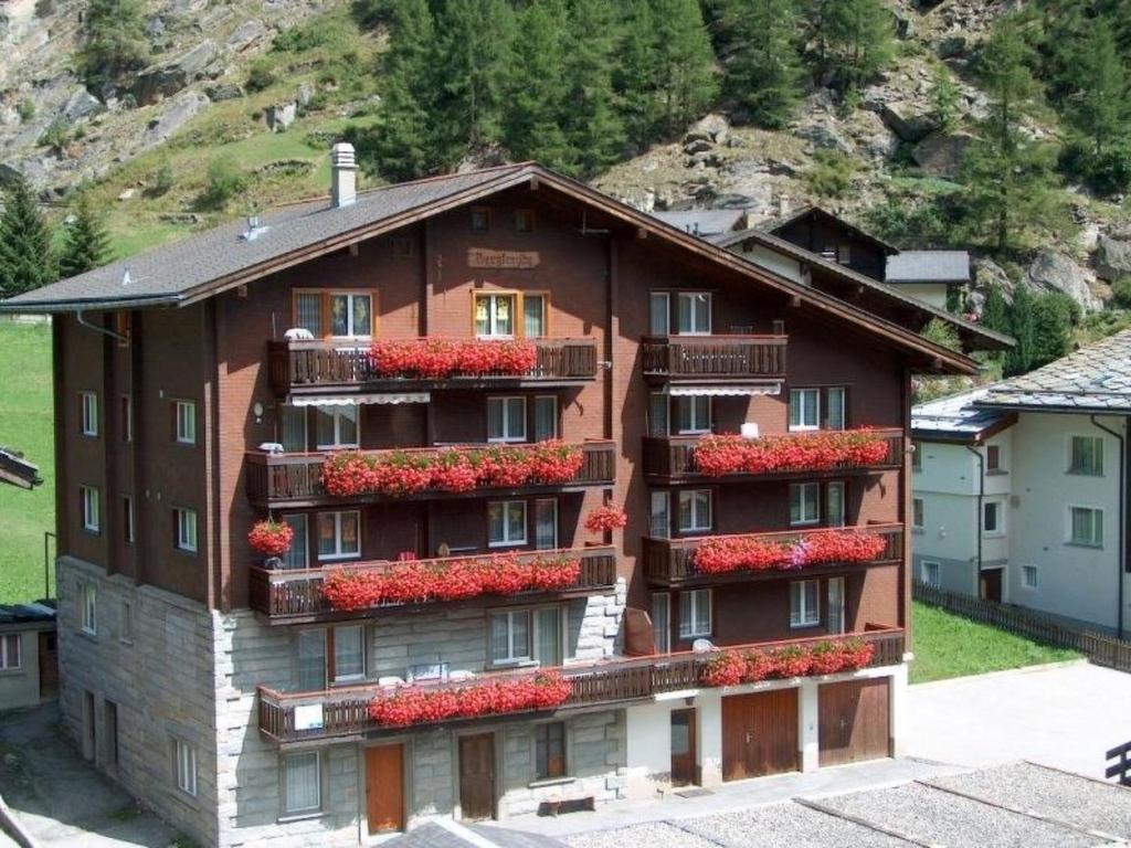 a building with red flowers on the side of it at Apartment Bergfreude by Interhome in Saas-Grund