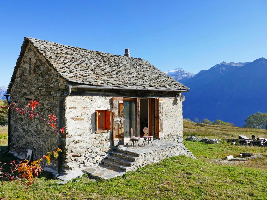 ein kleines Steinhaus auf einem Hügel mit Bergen im Hintergrund in der Unterkunft Holiday Home Rustico Andrea by Interhome in Acquarossa