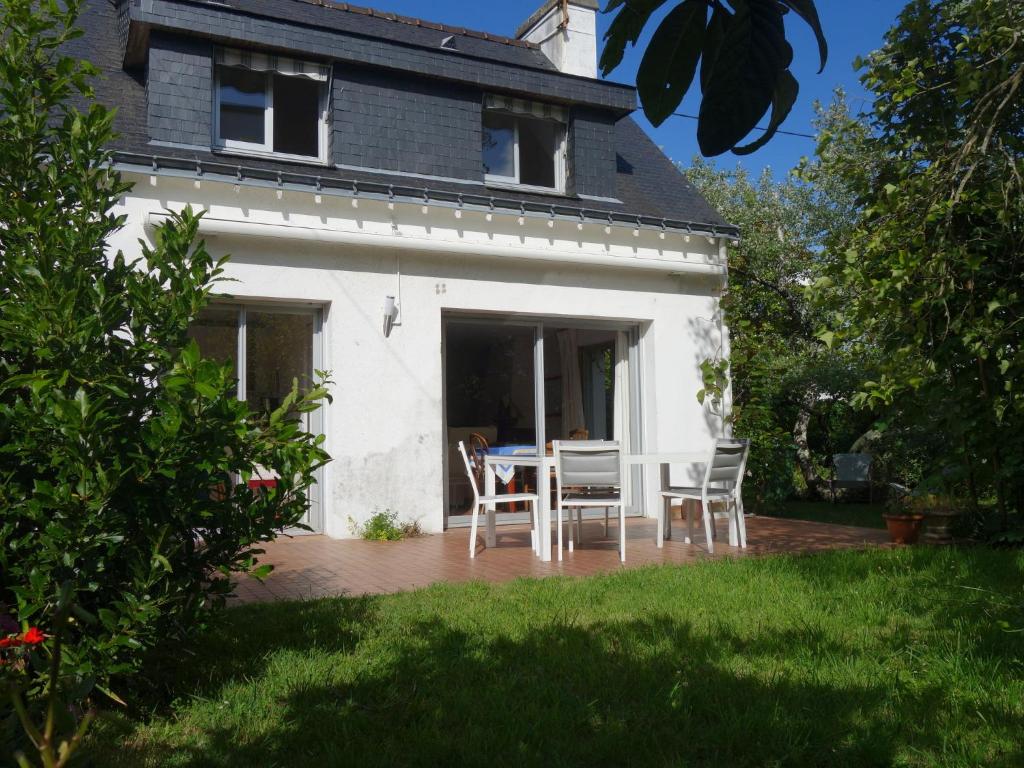 een wit huis met een tafel en stoelen op een patio bij Holiday Home Ty Mam Goz by Interhome in La Trinité-sur-Mer