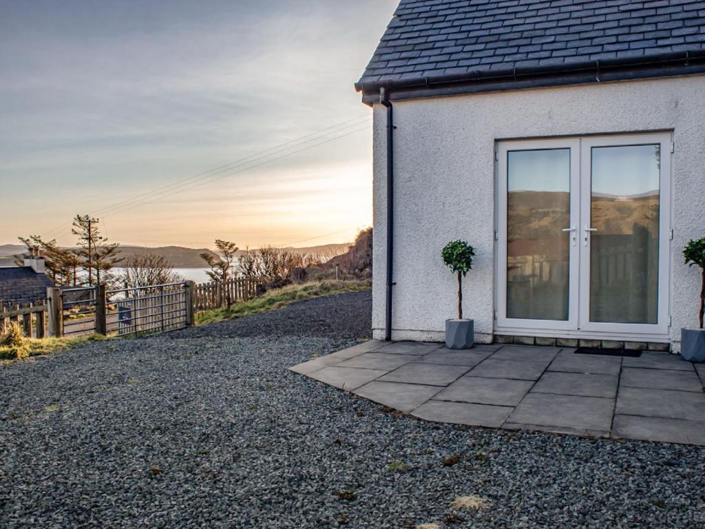 a white house with a window on a gravel driveway at Holiday Home Bay View by Interhome in Uig