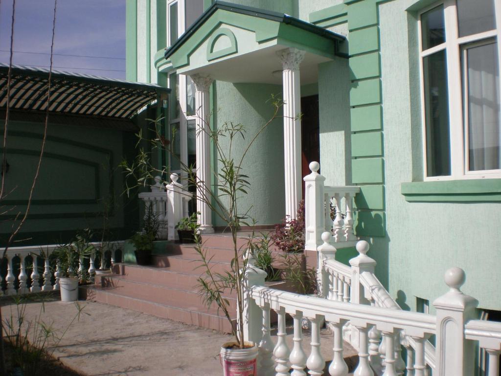 a house with a white fence and a porch with potted plants at Jahongir B&B Tashkent in Tashkent