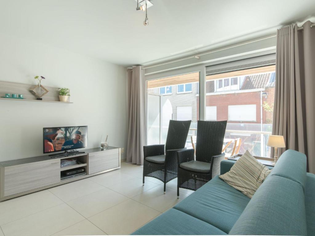een woonkamer met een blauwe bank en stoelen bij Apartment Residentie Seaside by Interhome in Bredene
