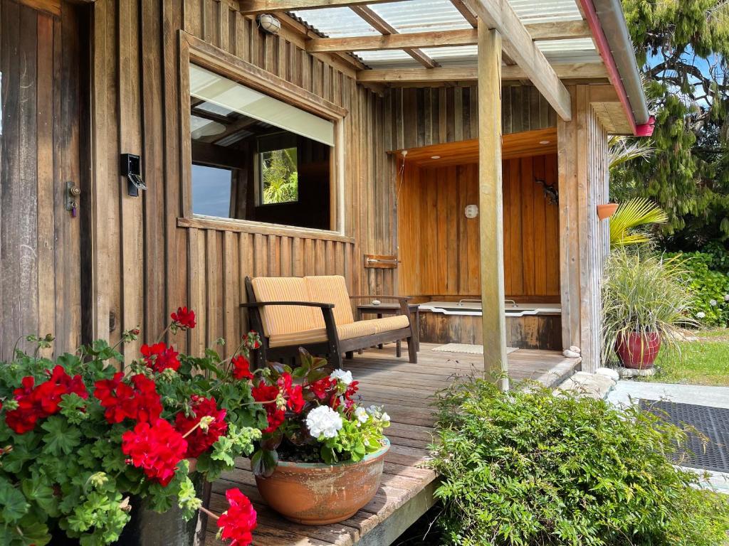 eine Holzterrasse mit Blumen und einem Stuhl darauf in der Unterkunft Hydrangea Cottages in Punakaiki
