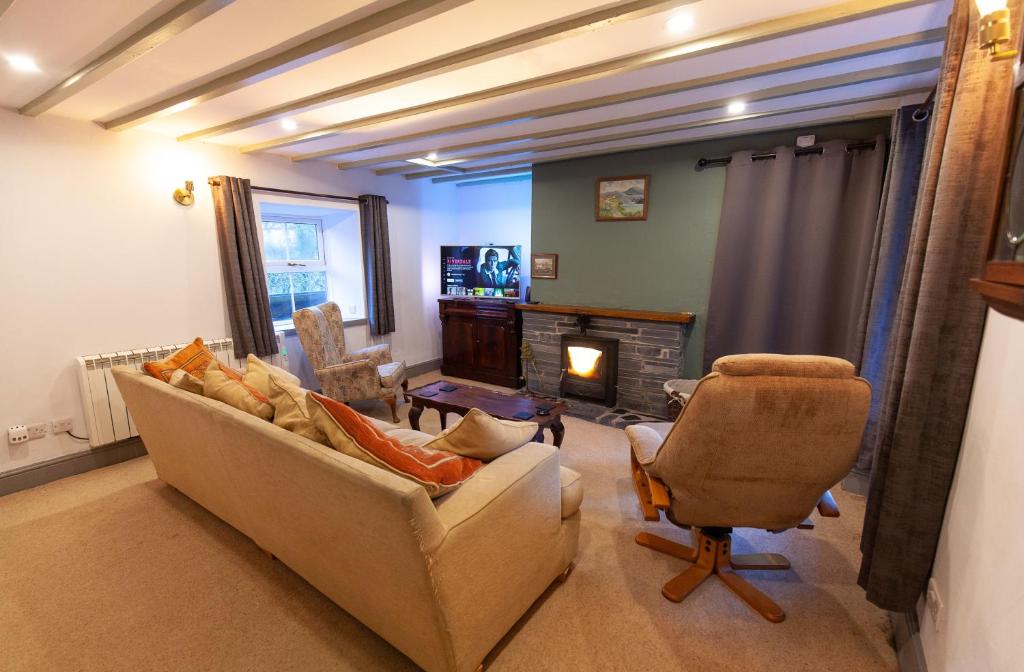 sala de estar con sofá, silla y chimenea en Country Cottage In The Dyfi Valley, en Corris