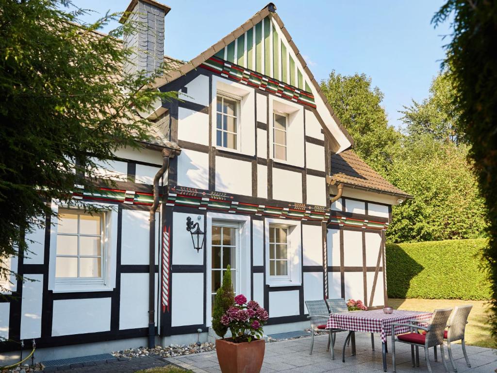 uma casa branca e preta com uma mesa e cadeiras em Holiday Home Am Golf- und Reitpark by Interhome em Niederhelden