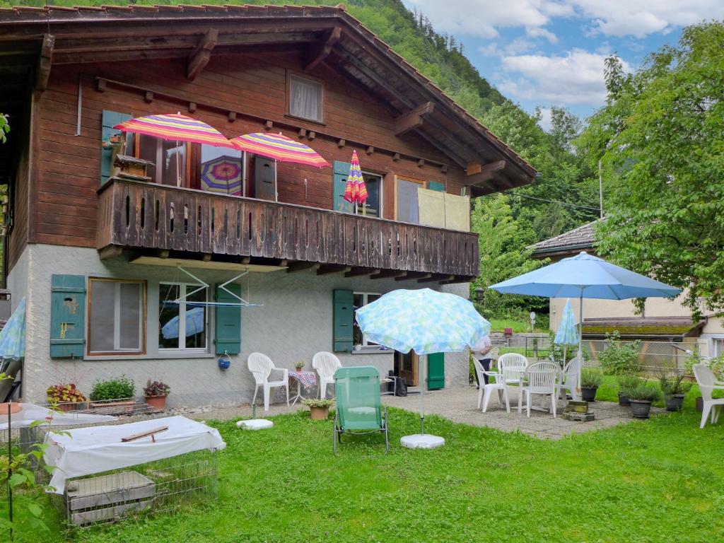 a house with a balcony with chairs and umbrellas at Apartment Erika by Interhome in Meiringen
