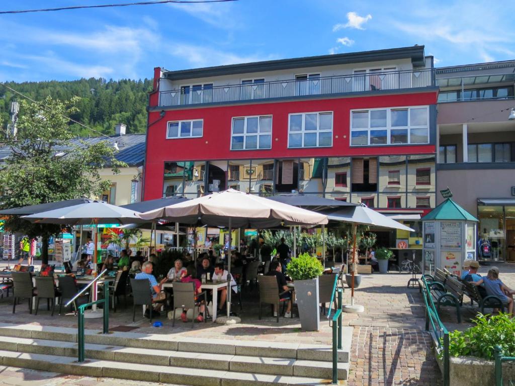 a red building with people sitting at tables and umbrellas at Apartment Papa Joe's Kuschelappartements-2 by Interhome in Schladming