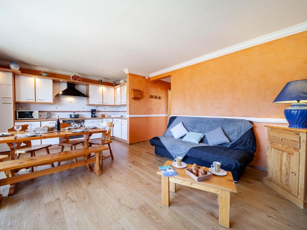 un salon avec un canapé bleu et une cuisine dans l'établissement Apartment Baikonour-6 by Interhome, au Corbier