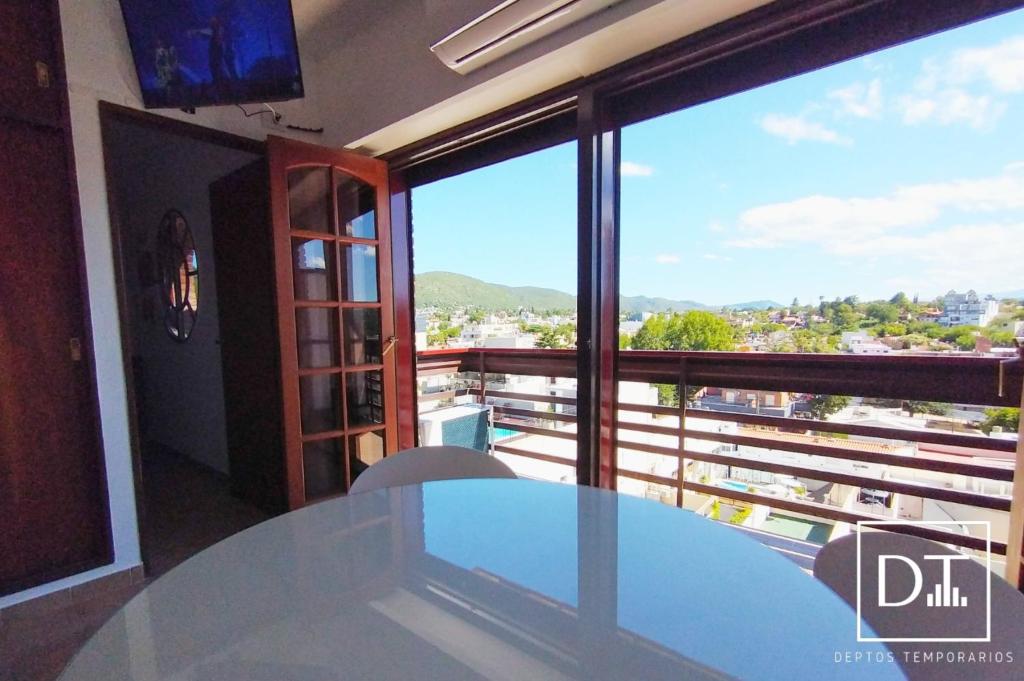 uma mesa num quarto com vista para uma varanda em Depto Las Heras em Villa Carlos Paz