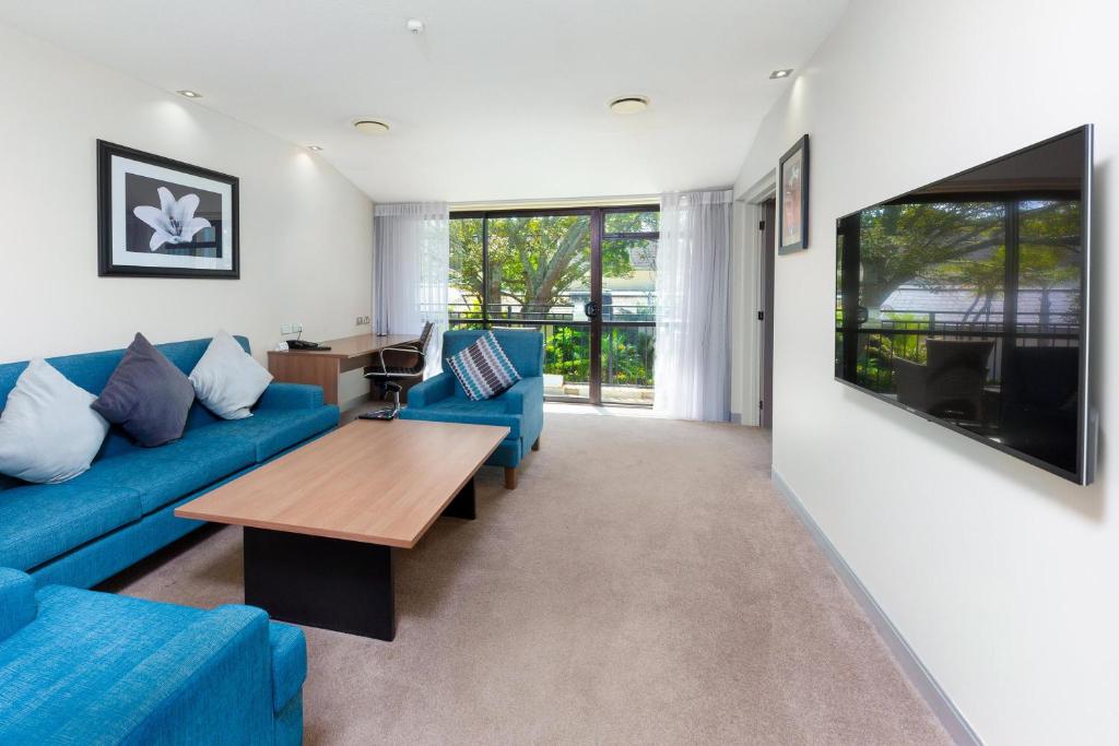 a living room with a blue couch and a table at Holiday Inn Auckland Airport by IHG in Auckland