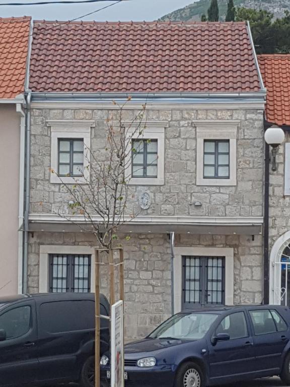 a stone house with two cars parked in front of it at Kamena kuća-Stone house in Trebinje