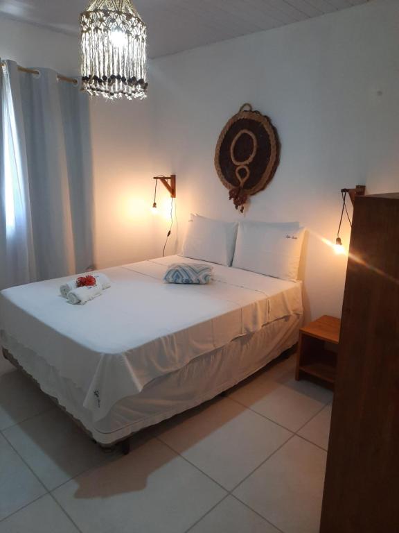 um quarto com uma grande cama branca e um lustre em Xêpa Suítes Economy em São Miguel do Gostoso